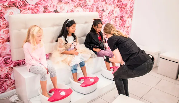 3 girls getting a feet soaking and nail polishing by an adult woman